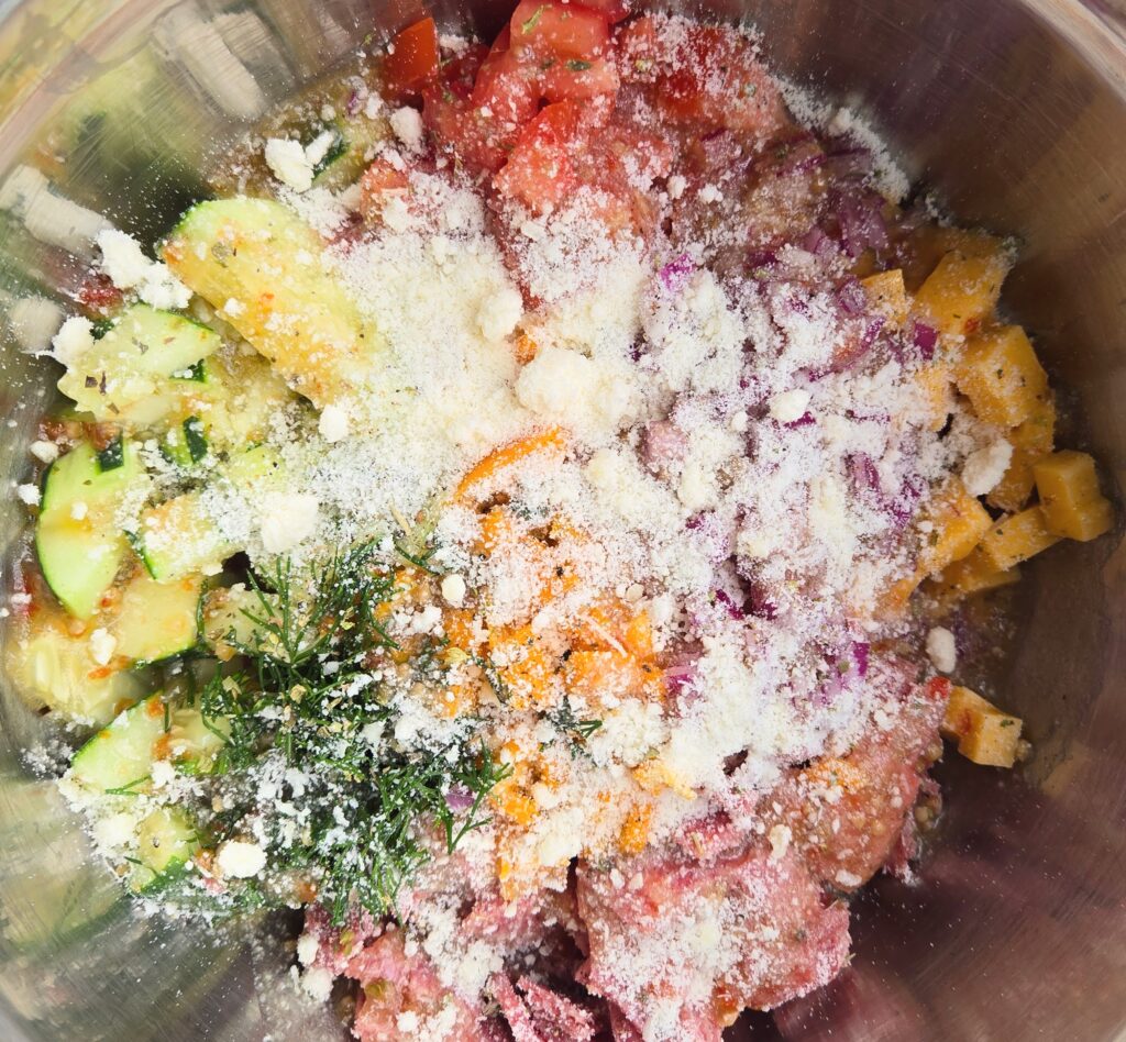 A bowl of sliced cucumbers, cheese, salami, red onion, tomato, fresh herbs and Italian dressing fresh dill 