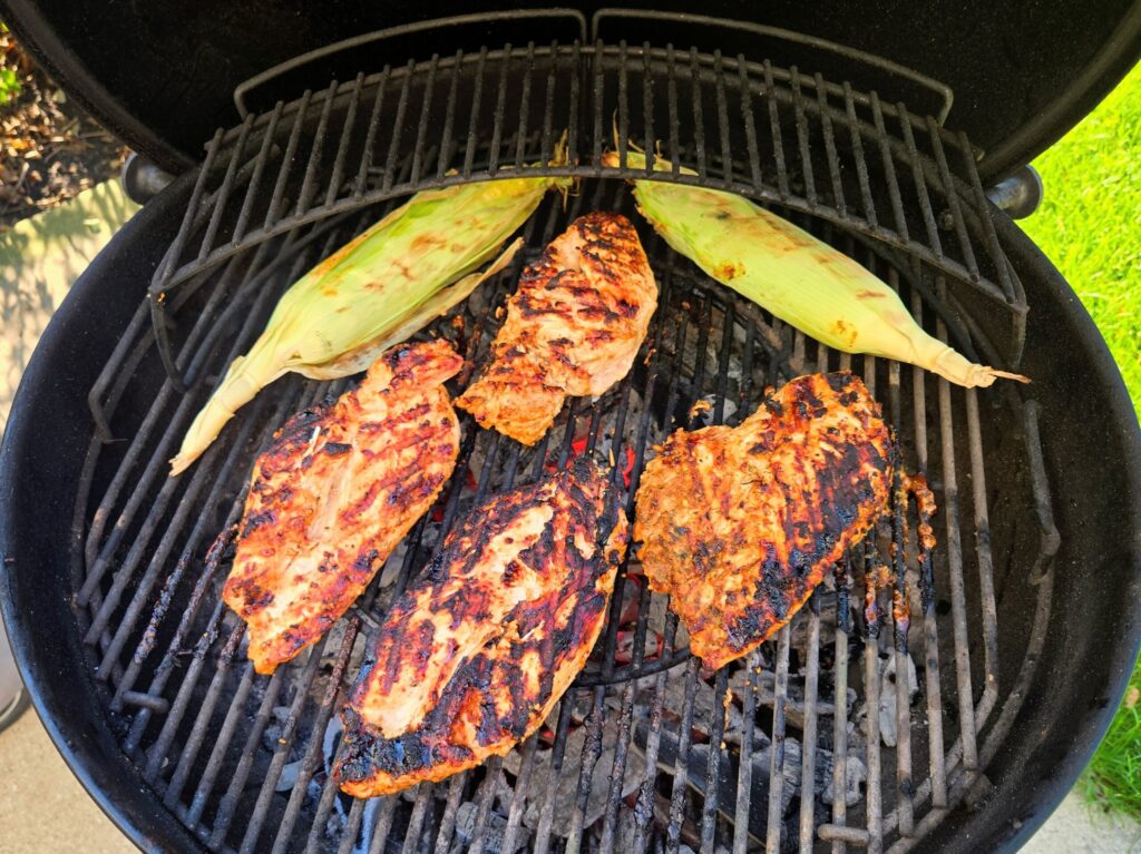2 ways I cook in the Summer without turning on the oven 5 Chicken breasts, corn in the husk, and asparagus cooking on an outdoor grill on a summer evening